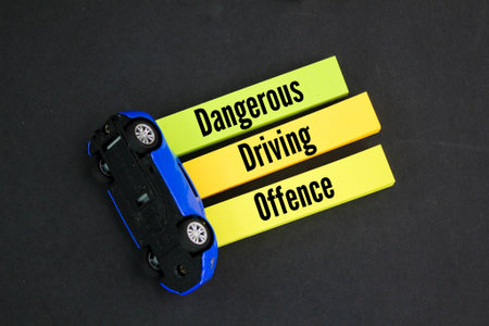 overturned car and colored paper with the word dangerous driving offence