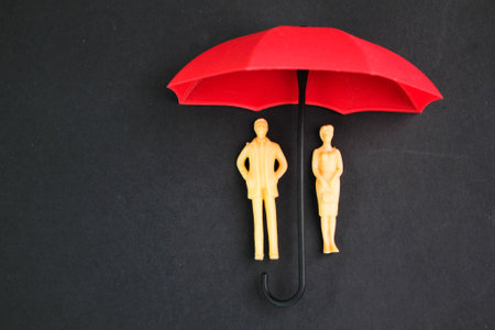 two miniature couples under an umbrella. the concept of old age protection. Concept of old age insuranceの写真素材