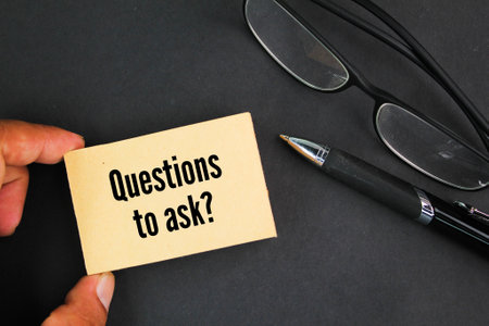 glasses, pen and paper with the words Questions to askの写真素材