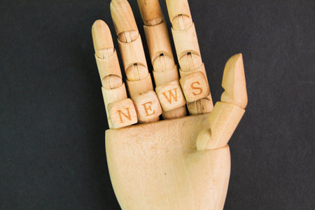 hand and wooden alphabet letters with the word news. the concept of new news or reporters