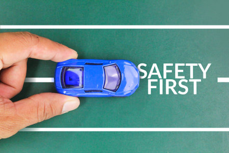 hand holding the car with the words SAFETY FIRST, to remind the driver to drive carefully and avoid distraction while on the road. safe driving conceptの写真素材