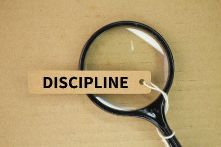 magnifying glass and tag paper with the word discipline. practice of training oneself to follow rules or a code of behavior, often through self-control and perseveranceの写真素材