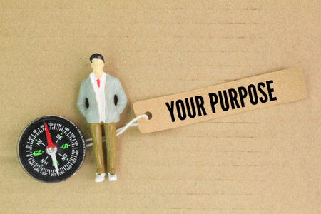 a compass, a miniature person and a paper tag with the word your purpose. concept of what your...