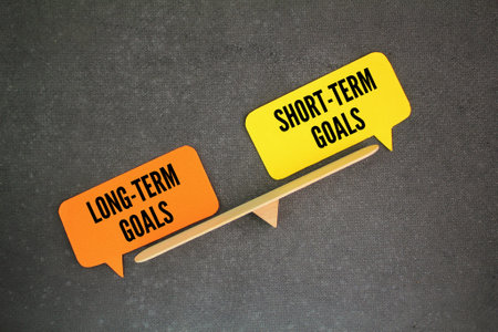the balance between the words Short-Term Goals vs Long-Term Goals. goal conceptの写真素材