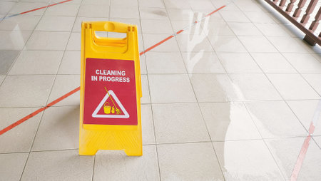 Yellow warning signs and water overflows have been put up to warn the public, cleaning is underway to prevent accidents on slippery roadsの写真素材