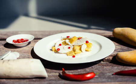 Thai exotic salad with chili pepper, mango and daikon - chinese radish on rustic wooden background. Authentic asian cuisine closeup.の写真素材