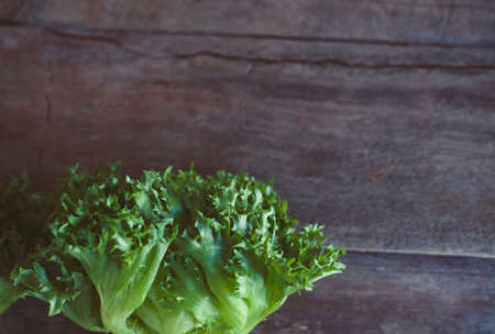 Letucce salad leaves on wooden background. Healthy food illustration. Salad ingridient closeup.