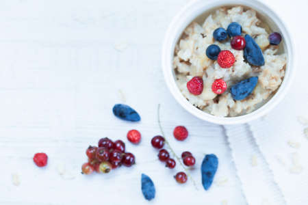 Top photo of breakfast menu with oatmeal and berries on white wooden backgroundの写真素材