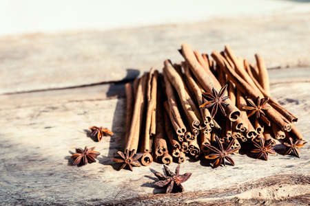 Artistic closeup of cinnamon and star anise seeds on a wooden background. Sunny still life photo.