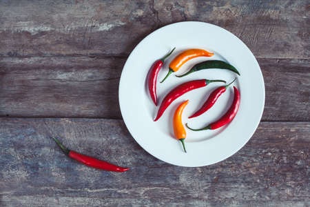 Hor chili peppers on a plate on a wooden background. Asian and mexican spice photo taken from the top.の写真素材