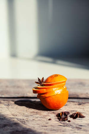 Artistic closeup of orange, cinnamon and star anise seeds on a wooden background. Sunny still life...
