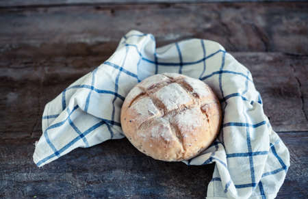 Close up photo of fresh baked bread on rustic wooden background with shallow depth of field.の写真素材