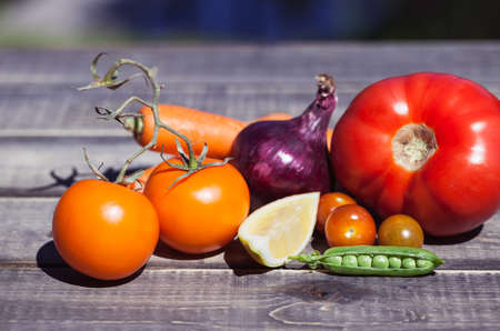 Bunch of fresh vegetables on a wooden table outside, sunny weather. Vegetarian food and healthy lifestyle.の写真素材