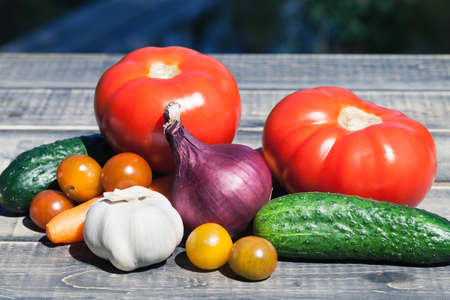 Bunch of fresh vegetables on a wooden table outside, sunny weather. Vegetarian food and healthy lifestyle.の写真素材