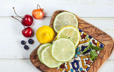 Top view photo of lime and lemon slices, blueberrues and cherry. Summer fruit and berry snack on...
