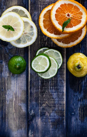 Artistic top view photo of different citruses - lemon, lime, orange - on rustic wooden background....