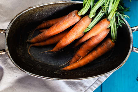 Organic carrots over rustic wooden background closeup. Top view of organic vegetables.