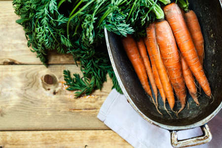 Organic carrots over rustic wooden background closeup. Top view of organic vegetables.の写真素材