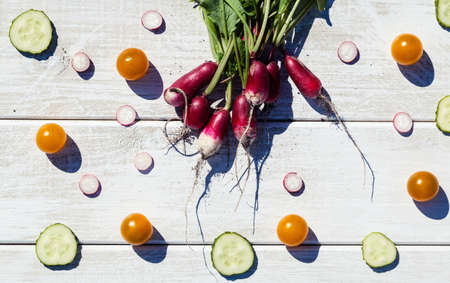 Artistic vacro photo of a bunch of farm grown radish surrounded by cucumber and tomatos. Organic natural food.の写真素材