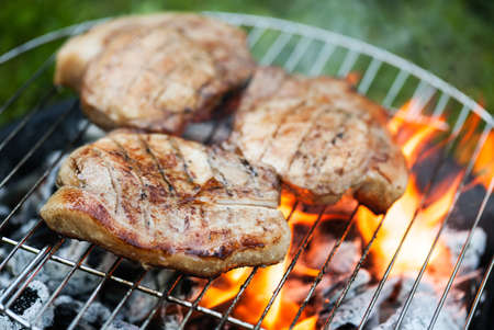 Top sirloin steak on a barbecue, shallow depth of field. Summer BBQ closeup, outdoor grill concept. Grilled steak meat cooked on carocal.の写真素材