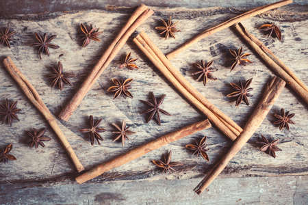 Artistic closeup of cinnamon and star anise seeds on a wooden background. Sunny still life photo.