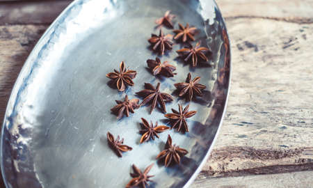 Artistic closeup of star anise seeds on a wooden background. Sunny still life photo.の写真素材