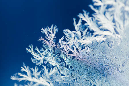Magical frost ornaments on the window. Closeup of frozen ice on the glass. Macro shot with shallow...