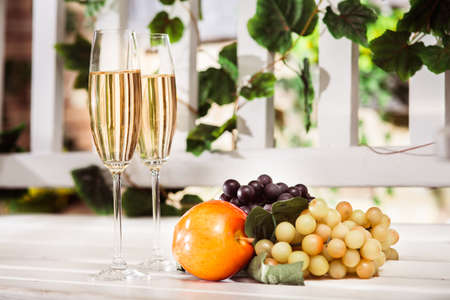 Autumn fruits and two glasses of white wine at the light background. Horizontalの写真素材