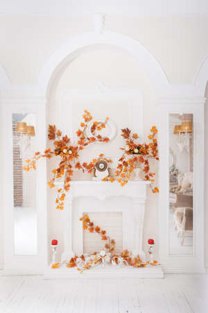 White classical fireplace in large hall with autumn decorationの写真素材