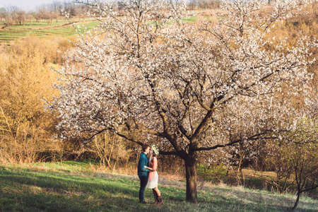 Love and tenderness. Beautiful young loving couple embracing in blossom spring garden. Romantic dating.の写真素材