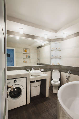 Bathroom with lavatory pan, hygienic shower, modern style sink and laundry washer. Scandinavian interior design of water closet.の写真素材