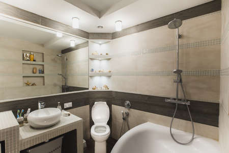 Interior design of a luxury bathroom, washroom with washbasin (sink), bathtub, huge mirror and seashells on the counter. Horizontalの写真素材