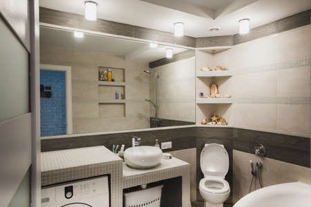 Interior design of a luxury bathroom, washroom with washbasin (sink), bathtub, huge mirror and seashells on the counter. Horizontalの写真素材