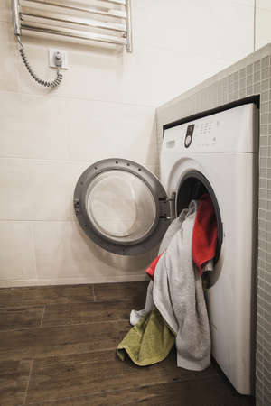 Washing machine with multicolored dirty towels inside. Side view. Verticalの写真素材