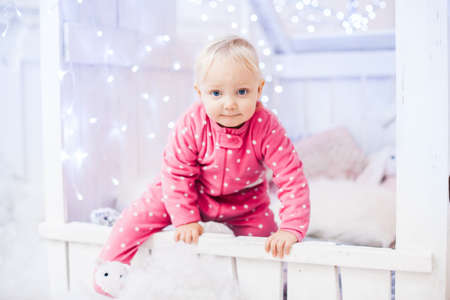 caucasian baby girl a little girl climbs out of the window of a wooden children's houseの写真素材