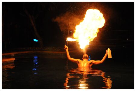 A fire-eater performs while standing in a pool at nightのeditorial素材