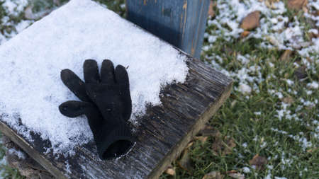A single black glove sitting on a snowy bench during the dayの写真素材