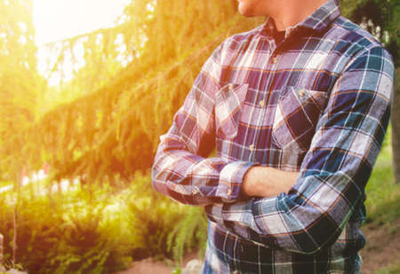 Man standing with arms crossed in park. Man waiting in park. Photo stock.