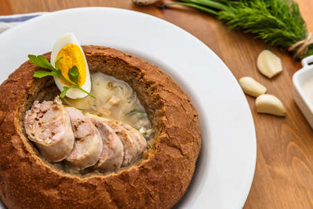 traditional white borscht zurek with sausage,egg and mushrooms in bread as bowlの写真素材