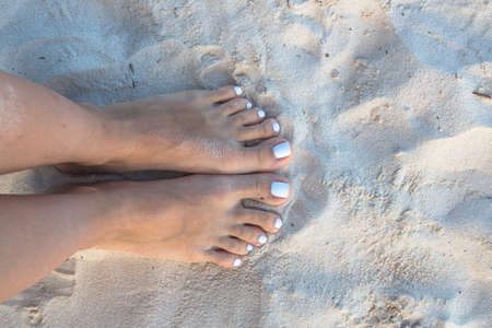 Two female bare feet on white sand.の写真素材