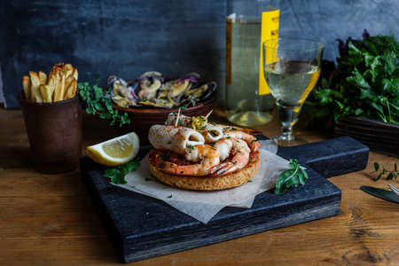 Grilled toasts with squid and prawns. Dark photoの写真素材