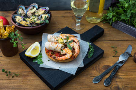 Italian food. Bruschetta with squid and prawns, tomatoes and parsleyの写真素材