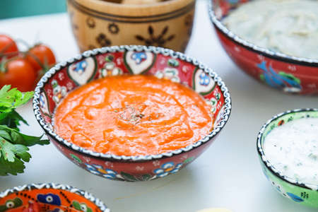Small bowls of homemade harissa and tzatziki with meze on a table