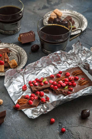 Chocolate bar with berries and nuts in foil on dark backgroundの写真素材