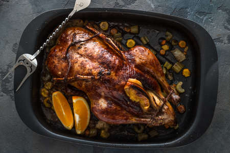 Roast duck with oranges and apples in a frying pan, dark photo, top view.の写真素材