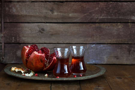 Fresh pomegranates and juice on copper plate. On wooden background. Free space for text. Place for wordingの写真素材