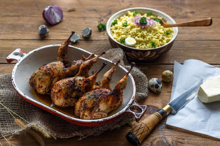 Delicious fried quails with eggs with bulgur porridge on a wooden table, rustic style. Top viewの写真素材