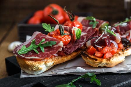 Close up bruschetta with proschuto, tomato, parmesan cheese and arugulaの写真素材