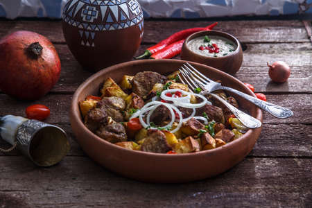 Big ceramic plate with roasted meat and potatoes with onion and wine. Traditional Georgian dish ojaxuri.の写真素材