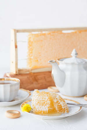 Cups of tea with honeycomb and bagels on a white background.